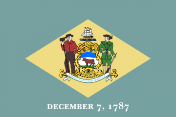 The state flag of Delaware, featuring a blue field with a buff-colored diamond at its center. Inside the diamond is the state coat of arms, which includes a shield with an ox, a ship above it, and figures of a farmer and a soldier on either side. Below the diamond, the date 'December 7, 1787' is displayed, marking Delaware as the first state to ratify the U.S. Constitution