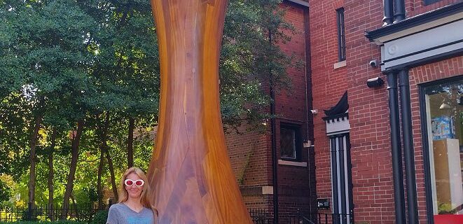 Visitor standing next to the World's Largest Chess Piece in St Louis - a 20-foot mahogany King outside the World Chess Hall of Fame