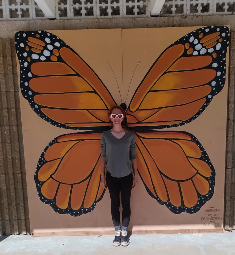 Visitor posing with monarch butterfly mural wings at The Papilion at Honor Heights Park in Muskogee, Oklahoma.