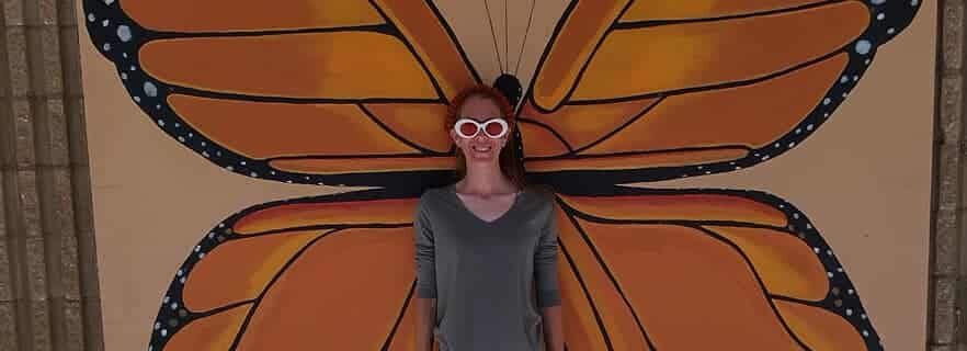 Visitor posing with monarch butterfly mural wings at The Papilion at Honor Heights Park in Muskogee, Oklahoma.