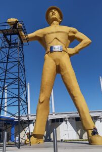 The Golden Driller standing proudly beside an oil derrick in Tulsa, Oklahoma, symbolizing the city’s deep roots in the petroleum industry.