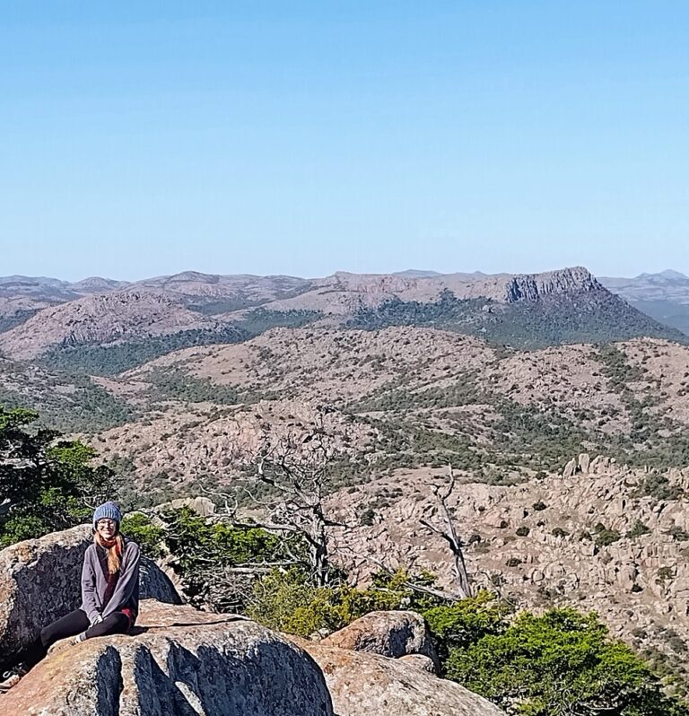 Hiker sitting on rocky outcrop enjoying Mount Scott Oklahoma summit views and mountain landscape