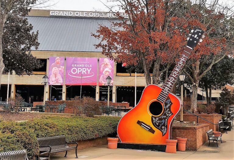 Colorful guitar sculpture in front of the Grand Ole Opry House in Nashville, Tennessee, with fall trees and performer banners in the background