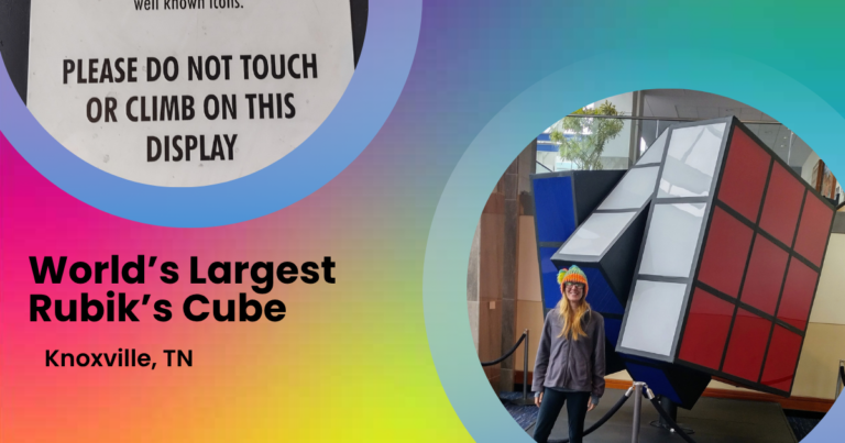 Nancy standing beside the giant Rubik’s Cube at the Knoxville Convention Center, with a warning sign that says not to touch or climb on the display.