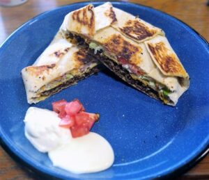 Grilled Crunchwrap Supreme cut in half, layers of filling visible with melted cheese and tomatoes.