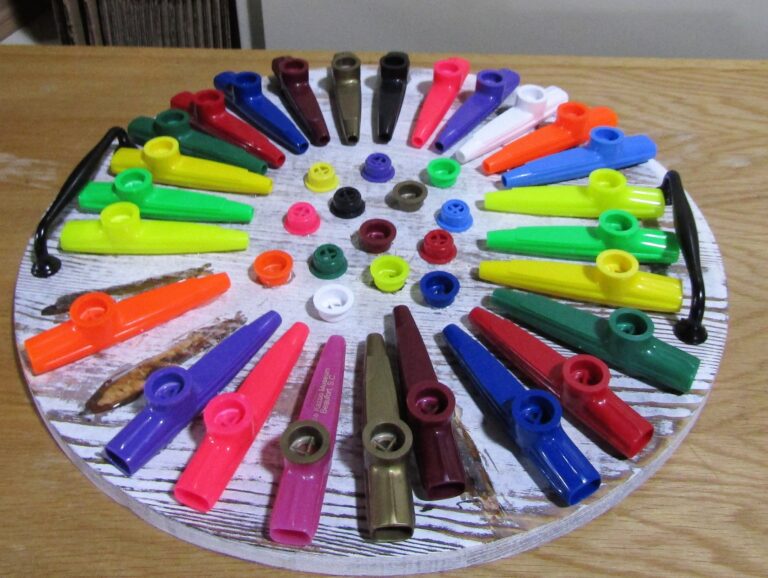 The Wheel of Kazoos” – a circular display of brightly colored plastic kazoos radiating out like rainbow sunbeams, center-capped with colorful resonator buttons. Pure kazoo chaos. Pure delight.