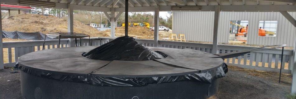 World's Largest frying pan displayed beneath a covered pavilion, with a brick platform and informational plaque in front.