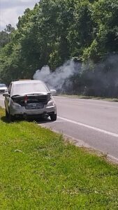 Zach mid-roadside chaos during our Michigan Bus Break: smoking hood, failed engine, and the aroma of charred drama