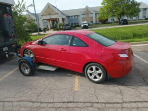Michigan Bus Break aftermath: red coupe being towed after roadside fiasco—Zach’s unintended car ballet meets mechanical consequence