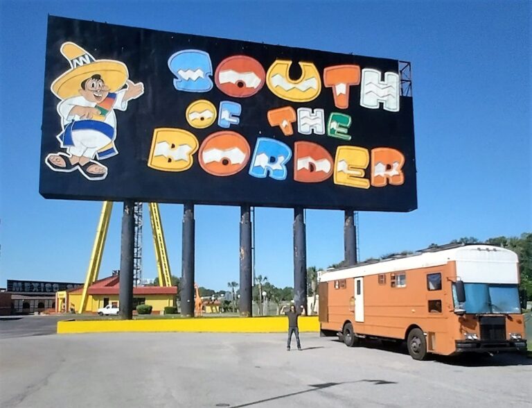 Colorful billboard at South of the Border Roadside attraction, featuring Pedro in a sombrero and poncho beside an RV, set under a clear Carolina sky.