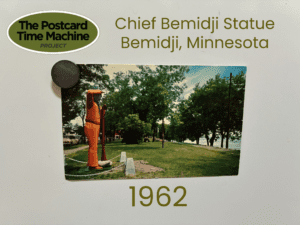Postcard from 1962 showing the Chief Bemidji Statue in Bemidji, Minnesota, surrounded by trees and a grassy park area.