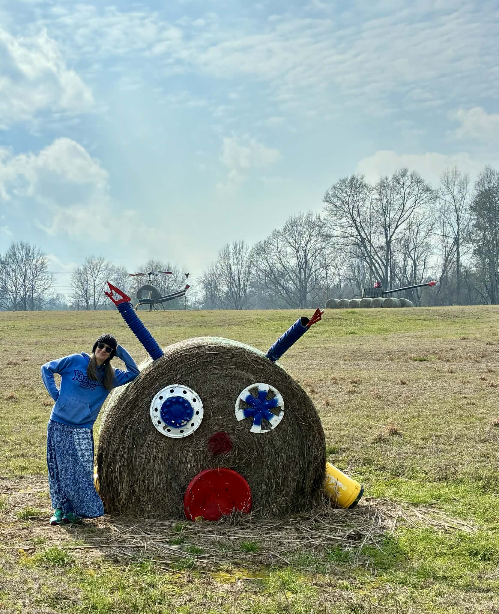 Nancy standing next to hay bale reindeer sculpture with googly eyes at Jim Bird's Hay Bale Art in Forkland Alabama