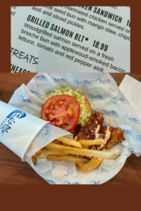 Grilled salmon BLT sandwich with bacon, lettuce, tomato, and fries at Salt Life Food Shack