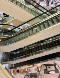 Multiple escalators crisscrossing across several floors inside Furnitureland South, with furniture showroom displays visible far below