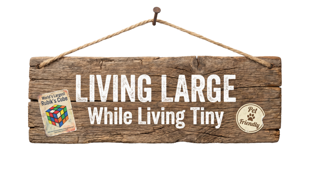 Living Large While Living Tiny logo on wooden plank hung by jute on a nail. 