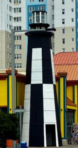 Black and White large lighthouse serving as the entrance to a boardwalk shop