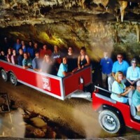 Tour tram inside Fantastic Caverns in Springfield, Missouri, carrying visitors through illuminated cave formations with stalactites overhead.