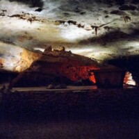 Illuminated cave chamber at Fantastic Caverns in Springfield, Missouri, featuring reddish rock formations and hanging stalactites under dramatic lighting.