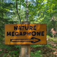 Directional sign reading 'Nature Megaphone' with arrow — trail marker at Agnes Andreae Nature Preserve Michigan, forest backdrop