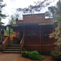 Entrance to Garlyn Zoo in Naubinway, Michigan, showing a rustic wooden building with “Entrance” and “Gifts & Souvenirs” signs, surrounded by trees and an elephant sculpture.