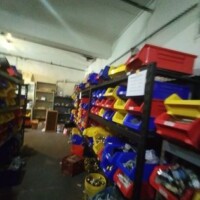 Interior view of a storage space at Refab St Louis Repurpose Shop, featuring metal shelves filled with colorful plastic bins containing assorted materials and salvage items for reuse and repurposing.