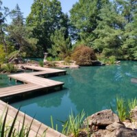 Wooden boardwalks winding over turquoise pond with fall foliage at Mizumoto Japanese Garden Springfield Missouri