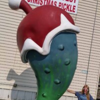 "You gonna eat that pickle?”—Fort Smith’s favorite festive brine towers in all its green glory. 🥒🎄 A person points at the World’s Largest Christmas Pickle sculpture in Fort Smith, AR—a 14-foot green pickle with a Santa hat, labeled by a sign above.