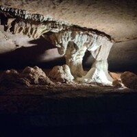 Inside War Eagle Cavern Arkansas, a massive column of mineral deposits rises where stalactite meets stalagmite, lit to show every drip‑formed detail.