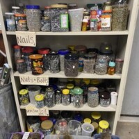 Shelving unit at Refab St Louis Repurpose Shop displaying glass jars filled with assorted hardware items including nails, nuts, bolts, and unsorted materials, each section labeled for easy salvage browsing and reuse.
