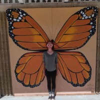 Visitor posing with monarch butterfly mural wings at The Papilion at Honor Heights Park in Muskogee, Oklahoma.