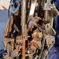 Close-up of welded metal components from the Optimus Prime statue at G&M Body Shop in Stillwater, Oklahoma. Gears, springs, pipes, and brackets form part of the robot’s lower structure, with sunlight highlighting rusted textures and industrial detail. Part of the Transformers statues Stillwater Oklahoma roadside display.