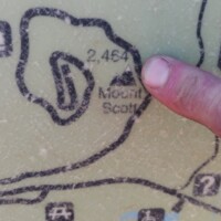 Close-up of trail map showing Mount Scott location with finger pointing to hiking routes