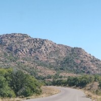 Road leading toward Mount Scott summit with rocky peak and clear blue sky