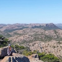 Hiker sitting on rocky outcrop enjoying Mount Scott Oklahoma summit views and mountain landscape