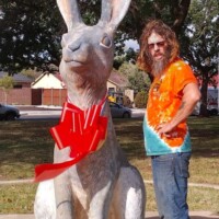 Person in orange shirt standing next to World's Largest Jackrabbit statue with red bow in Odessa Texas