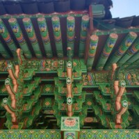 Close-up of the painted eaves and beams of the H.U. Lee International Gate in Little Rock, showcasing vibrant dancheong patterns in green, red, and blue; traditional Korean motifs and floral designs highlight the craftsmanship and cultural heritage of the gate’s architecture.