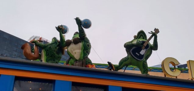Green frog statues playing instruments on a rooftop