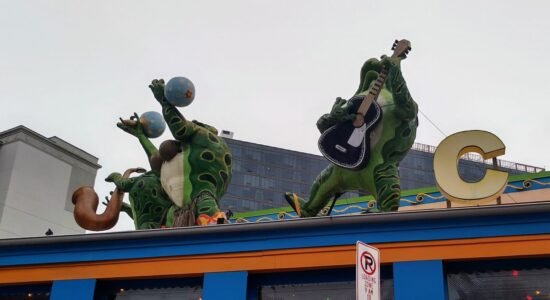 Green frog statues playing instruments on a colorful building rooftop