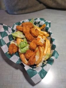Fried chicken tenders and french fries with lettuce in a basket lined with checkered paper