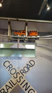 Indoor railroad crossing sign with a model train on an elevated track above