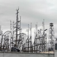 Cluster of tall communication and radio towers at Billy Tripp’s Mindfield Brownsville TN, equipped with antennas, dishes, and a spherical radar structure above an industrial rooftop.
