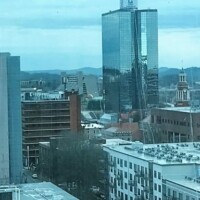 Downtown Knoxville aerial view – Urban skyline, trees, and rolling hills seen from the Sunsphere.