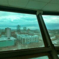 Sunsphere window view – Knoxville TN cityscape framed by large glass panels, with urban buildings and rolling hills.
