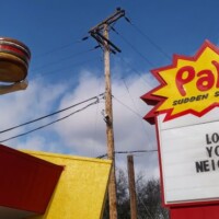 Pal’s Sudden Service building at 4224 Fort Henry Drive, Kingsport, TN, with giant fiberglass statue on roof and “Love Your Neighbor” sign.