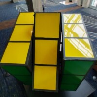 Side view of the world’s largest Rubik’s Cube sculpture at the Knoxville Convention Center, featuring vibrant yellow and green faces stacked at playful angles
