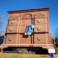 The World's Largest Chest of Drawers towering over the street in High Point, North Carolina, with a pair of colorful socks hanging from an open drawer—a playful nod to the city's furniture industry.