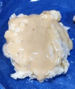 Biscuits covered in gravy on a blue plate