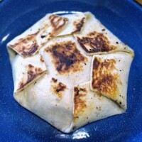Grilled Crunchwrap folded into a hexagon with visible sear marks on top, served on a blue plate as the final toasted version of the copycat recipe.
