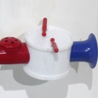 Red, white, and blue drum-style kazoo mounted on the wall—complete with snare-like ridges and side tabs that look ready for a solo. Equal parts musical toy and patriotic percussion mystery.
