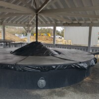 World's Largest frying pan displayed beneath a covered pavilion, with a brick platform and informational plaque in front.